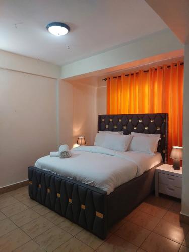 a bedroom with a large bed with an orange curtain at Dobajo Homes2 in Kisumu