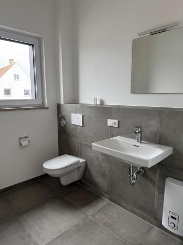 a bathroom with a sink and a toilet and a mirror at Horgau Living in Horgau