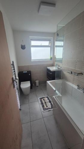 a bathroom with a tub and a toilet and a sink at Brooklyn House in Elmers End