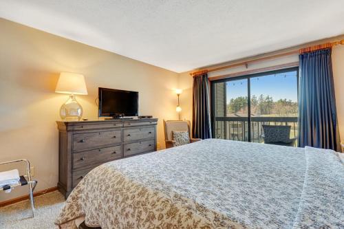 a bedroom with a bed and a television and a window at Chetola Cardinal 201 in Blowing Rock