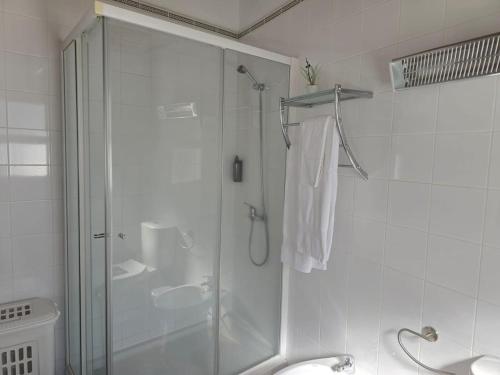 a white bathroom with a shower and a sink at Casa Poço Azul in Achadinha