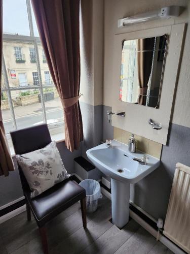 a bathroom with a sink and a chair and a mirror at Spalite Hotel in Gloucester