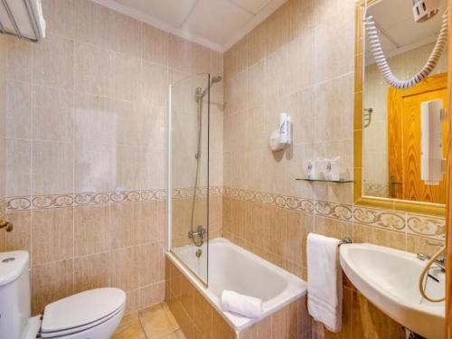 a bathroom with a toilet and a sink and a tub at Hotel Torre San Juan in San Juan de Alicante