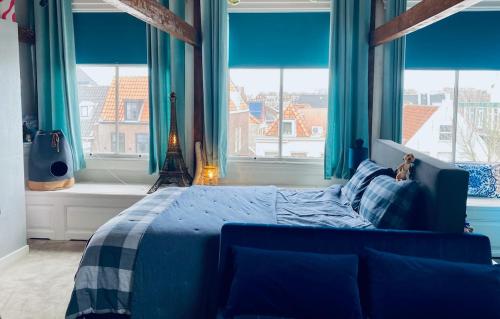 a bedroom with a blue bed with blue curtains and windows at Boutique Home in Maassluis