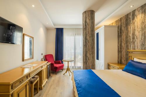 a hotel room with a bed and a desk and a red chair at Minerva Hotel Kızkalesi in Kizkalesi