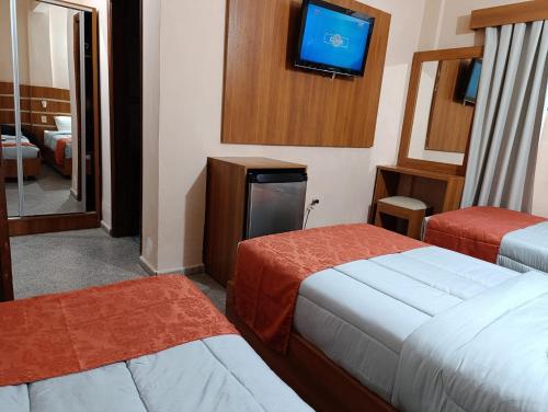 a hotel room with two beds and a flat screen tv at Hotel Sancer in Coronel Oviedo