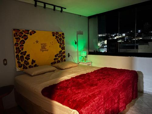 a bedroom with a bed with a red blanket and a window at Solar Boutique Residence in Pouso Alegre