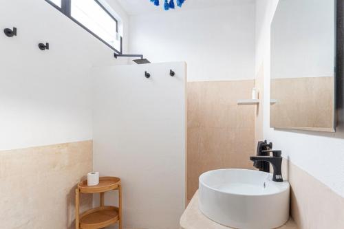 a white bathroom with a sink and a window at Casa La Gloria, Centro de Mérida, Hasta 16 Huéspedes in Mérida