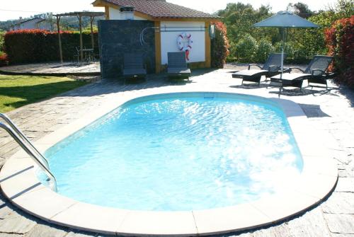 a swimming pool in a yard with chairs and an umbrella at Casa da Eira em Dornes - Casa de campo familiar com piscina in Dornes
