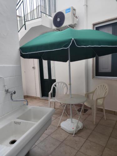a green umbrella sitting next to a table and chairs at La NICCHIA in Monteroni di Lecce