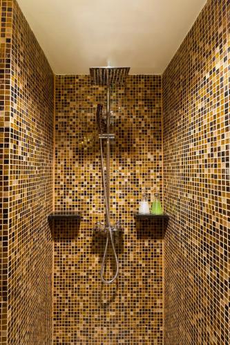 a bathroom with a shower with brown tiled walls at Asia Hotels Group (Poonpetch Chiangmai) in Chiang Mai
