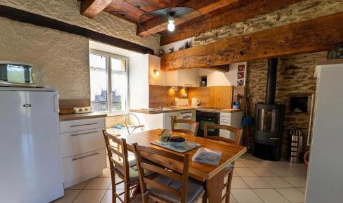 a kitchen with a wooden table and a white refrigerator at Gîte de Malavals in Castelnau-de-Mandailles