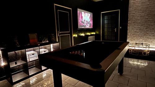 a dark room with a pool table and a television at La loge secrète Love Room in Dolus-le-Sec