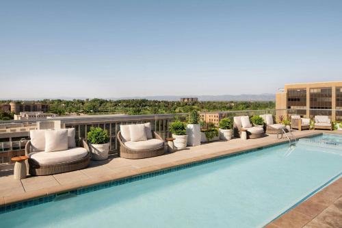 a pool on the roof of a building with lounge chairs at Halcyon - A Hotel in Cherry Creek in Denver