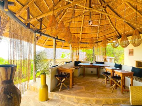 a restaurant with tables and chairs under a wooden roof at Basecamp Changani in Dar es Salaam
