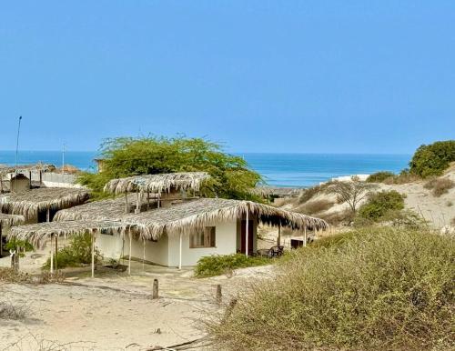 a small house with thatched roofs on a beach at Villa Vichayo Bungalows in San Martín