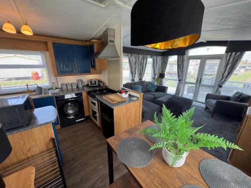 a kitchen and living room with a table in a caravan at Millfields Holiday Park - The Balmoral - Coastal Caravan Breaks in Ingoldmells
