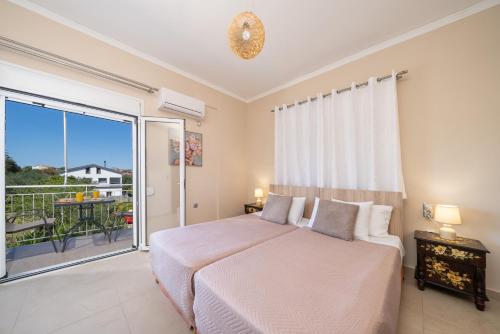 a bedroom with a large bed and a balcony at Gerasimos Dream House - 7 Minutes from the Airport in Lakíthra