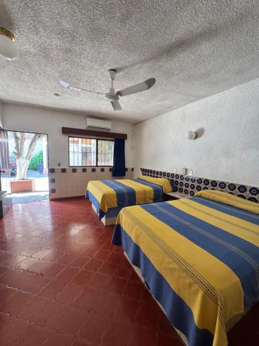 a room with four beds with yellow and blue sheets at Hotel California in Mazatlán