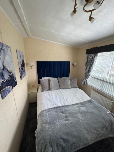 a bedroom with a large bed with a blue headboard at Millfields Holiday Park - The Balmoral - Coastal Caravan Breaks in Ingoldmells