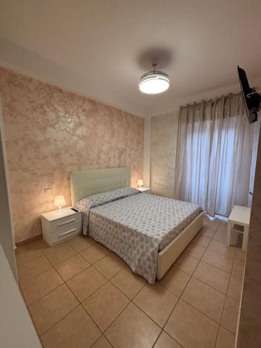 a bedroom with a bed and two tables and a window at Ludovica's house 2 in Giardini Naxos
