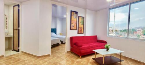 a living room with a red couch and a bed at Hospedarte Cali Sur in Cali