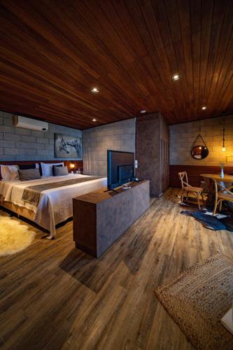 a bedroom with a bed and a desk and a television at Pousada Recanto do Sambaqui in Balsa Nova