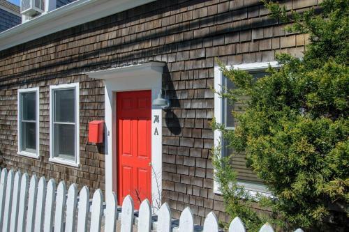 a red door on a house with a white fence at Steps to Commercial St Walk to Beach in Provincetown