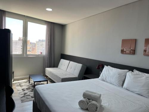 a hotel room with a bed and a couch at Town Co - Apartment 1004 in Porto Alegre
