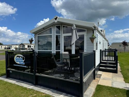 a screened in deck with a table in it at Golden Anchor - The Vogue - Coastal Caravan Breaks in Chapel Saint Leonards