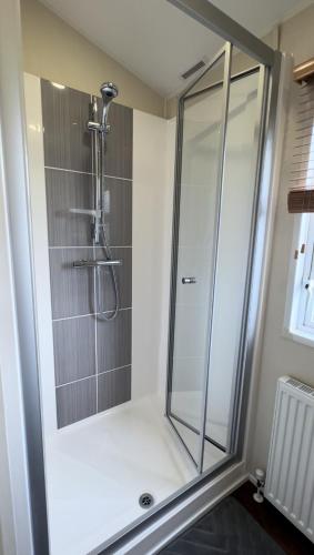 a shower with a glass door in a bathroom at Golden Anchor - The Vogue - Coastal Caravan Breaks in Chapel Saint Leonards