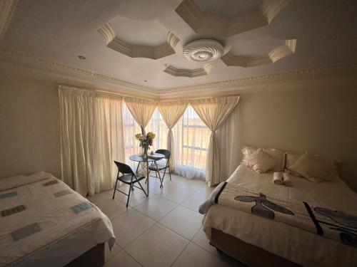 a bedroom with a bed and a table with chairs at Kingdoms Place Guesthouse in Ga-Luka