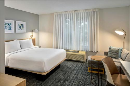 a hotel room with a large bed and a chair at TownePlace Suites Bowie Town Center in Bowie