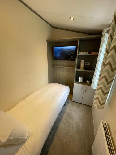 a small bedroom with a bed and a television at Golden Palm Resort - The Atlas Family - Coastal Caravan Breaks in Chapel Saint Leonards