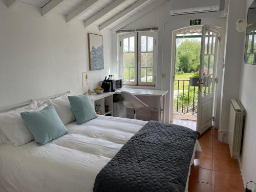 a bedroom with a bed and a desk and a window at Campos Essencia in Arganil