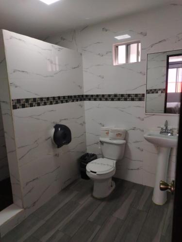 a white bathroom with a toilet and a sink at Hotel Agora in Ensenada