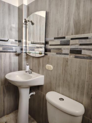 a bathroom with a sink and a toilet and a mirror at Del Sol Suites - Apartamento #1 in Guayaquil