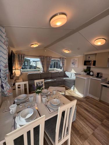 a kitchen and living room with a table and chairs at Golden Palm Resort - The Pearl - Coastal Caravan Breaks in Chapel Saint Leonards