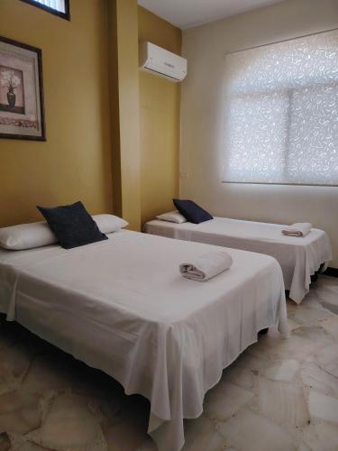 two beds in a room with a window at Del Sol Suites - Apartamento #1 in Guayaquil