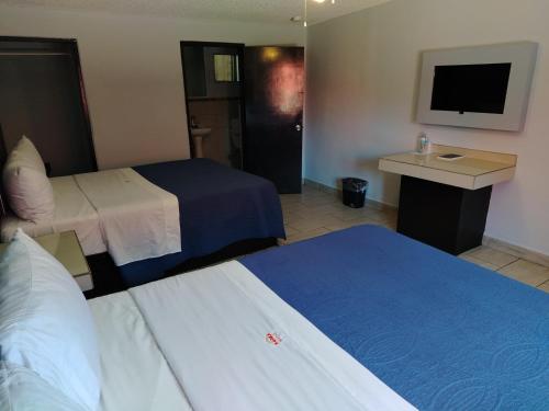 a hotel room with two beds and a television at Hotel Agora in Ensenada