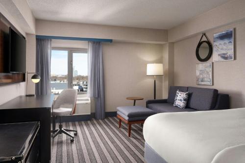 a hotel room with a bed and a couch and a chair at Courtyard by Marriott Boston Brookline in Brookline