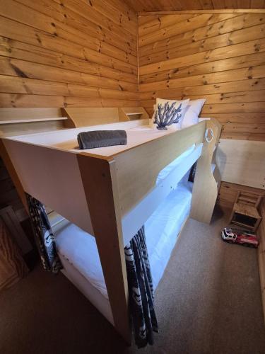 a bed in a room with a wooden wall at Surf Lodge in West Down