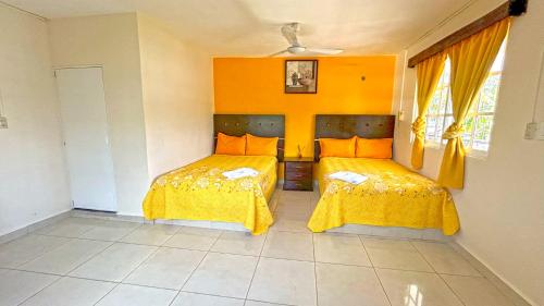 a bedroom with two beds with yellow covers at HOTEL REAL UCUM in Ocum