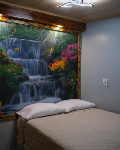 a bedroom with a painting of a waterfall at Kibutz Eco Guesthouse in Fortuna