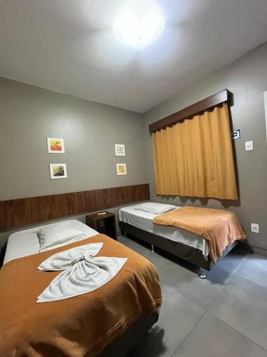 a room with two beds with towels on them at Hotel Casimiro in Ponta Grossa