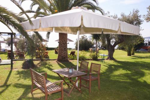 a table and chairs under a large umbrella at Angeliki Beach Hotel in Megali Ammos