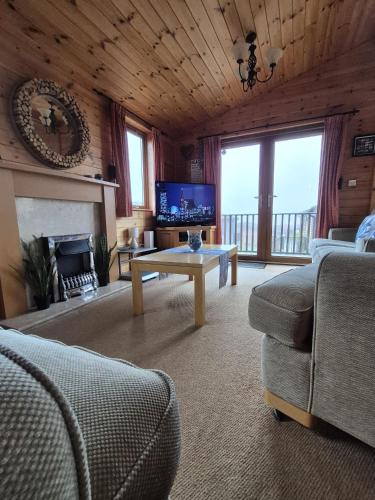 a living room with a couch and a table and a tv at Surf Lodge in West Down
