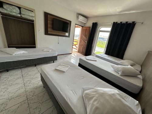 two beds in a room with a tv and a room with at Hotel e Restaurante Santa Fé in Lages