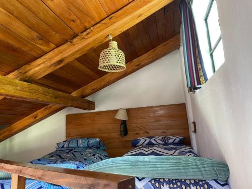 two beds in a attic bedroom with wooden ceilings at The Black Sheep Inn in Chugchilán