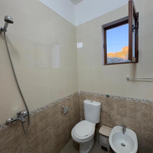 a bathroom with a toilet and a sink and a window at Orikum Holiday Apartaments in Orikum